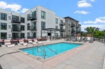 a swimming pool in front of an apartment building with a pool